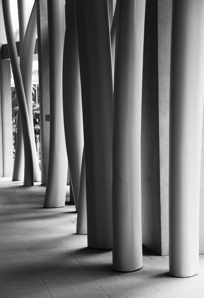 Vertical Grayscale Shot Of Modern Building S Interior With Crooked Columns